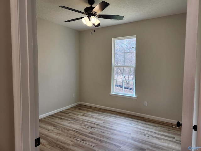 spare room featuring a textured ceiling, ceiling fan, wood finished floors, and baseboards