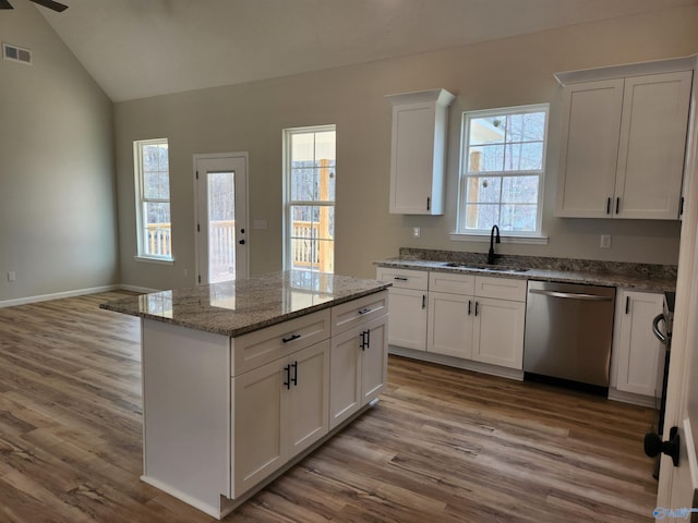 kitchen featuring lofted ceiling, visible vents, a kitchen island, a sink, and dishwasher