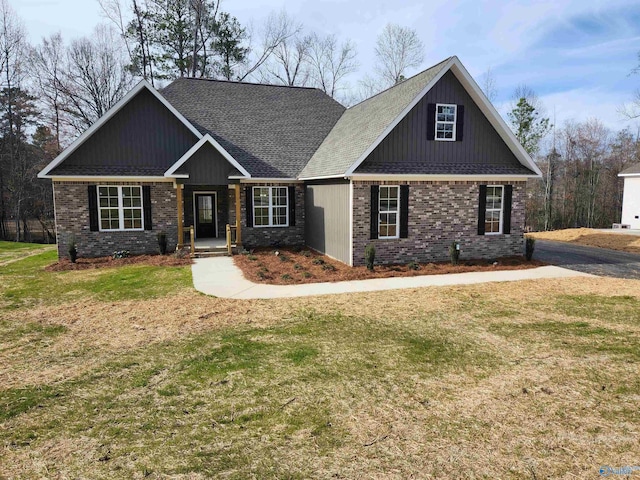 craftsman house featuring a shingled roof, a front yard, and brick siding