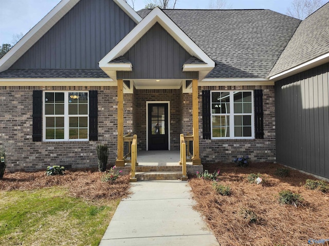 view of front of house with brick siding, a porch, a shingled roof, and board and batten siding