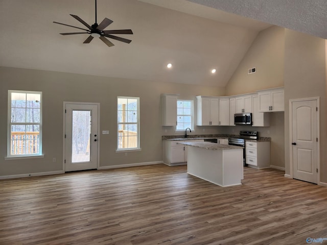 kitchen with a center island, appliances with stainless steel finishes, open floor plan, white cabinetry, and a sink