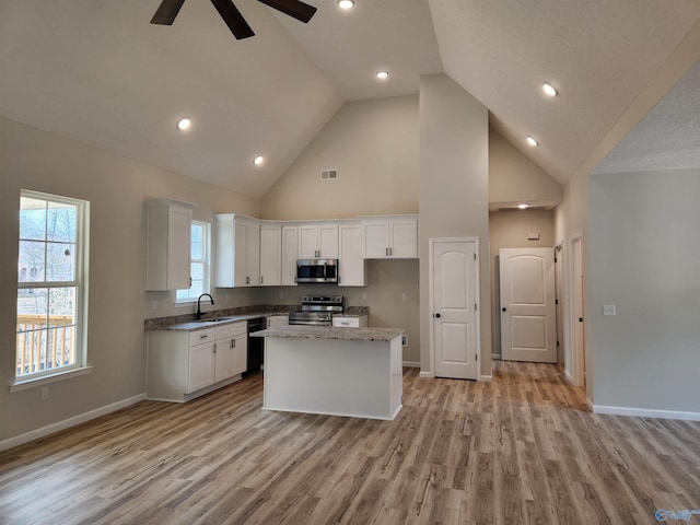 kitchen featuring a center island, stainless steel appliances, light wood-type flooring, white cabinetry, and a sink