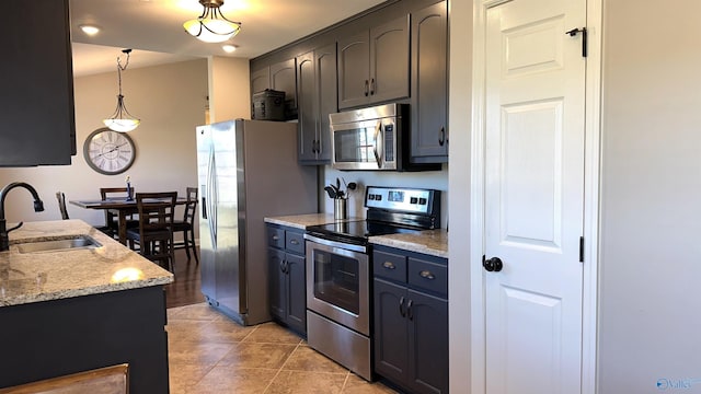 kitchen featuring light stone countertops, light tile patterned flooring, hanging light fixtures, stainless steel appliances, and a sink