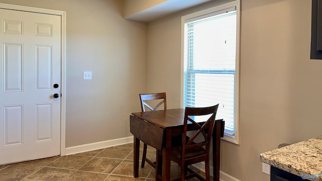 dining space featuring a wealth of natural light, baseboards, and dark tile patterned flooring