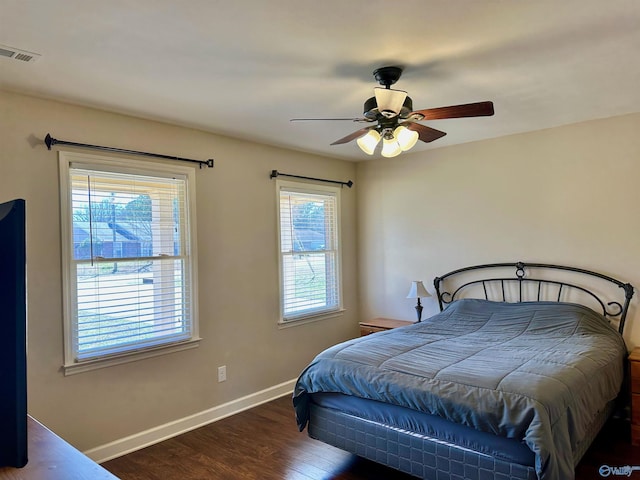 bedroom featuring a ceiling fan, wood finished floors, visible vents, and baseboards