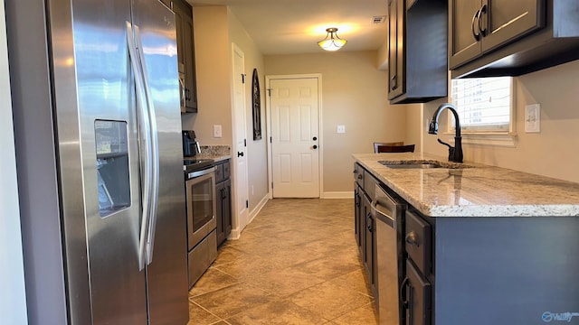 kitchen with light stone counters, visible vents, baseboards, a sink, and stainless steel refrigerator with ice dispenser