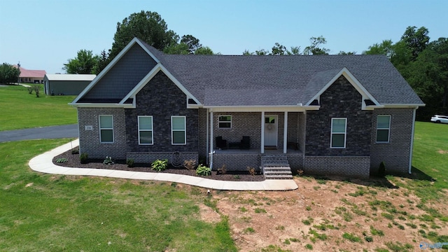 craftsman-style house with a front yard, brick siding, covered porch, and stone siding