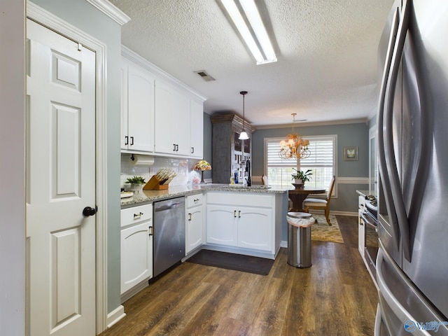 kitchen with white cabinets, kitchen peninsula, pendant lighting, stainless steel appliances, and a chandelier