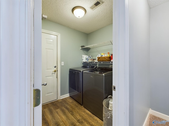 clothes washing area featuring a textured ceiling, dark hardwood / wood-style flooring, and washing machine and dryer