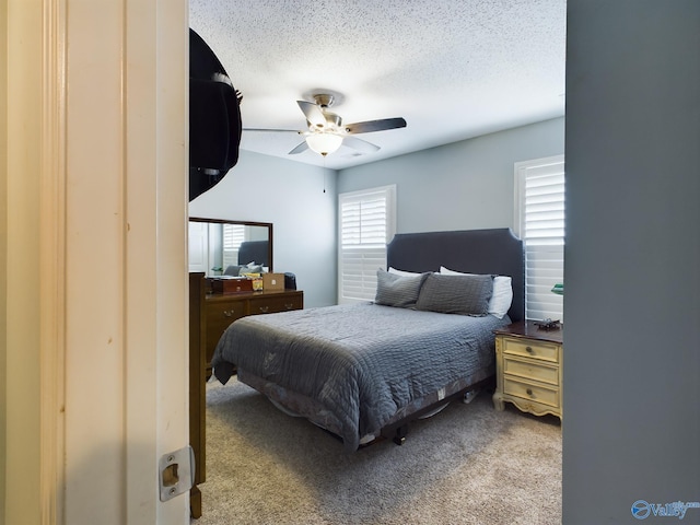 carpeted bedroom with ceiling fan and a textured ceiling