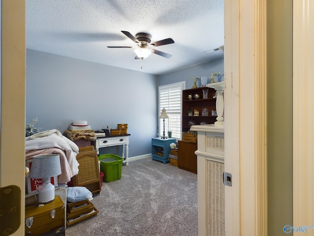 carpeted home office with ceiling fan and a textured ceiling