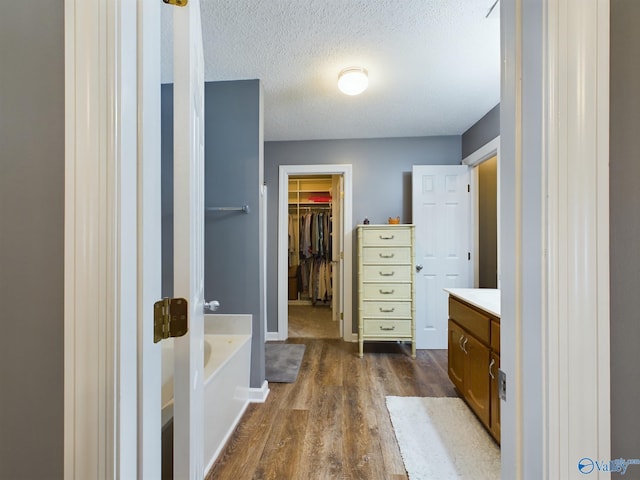 bathroom featuring a textured ceiling, wood-type flooring, vanity, and a tub