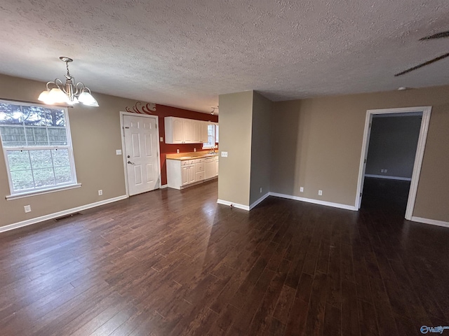 unfurnished living room featuring a textured ceiling, dark hardwood / wood-style flooring, and a notable chandelier