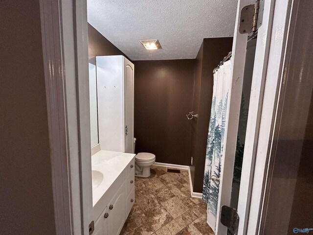 bathroom with vanity, toilet, and a textured ceiling