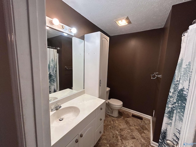 bathroom featuring vanity, a textured ceiling, and toilet