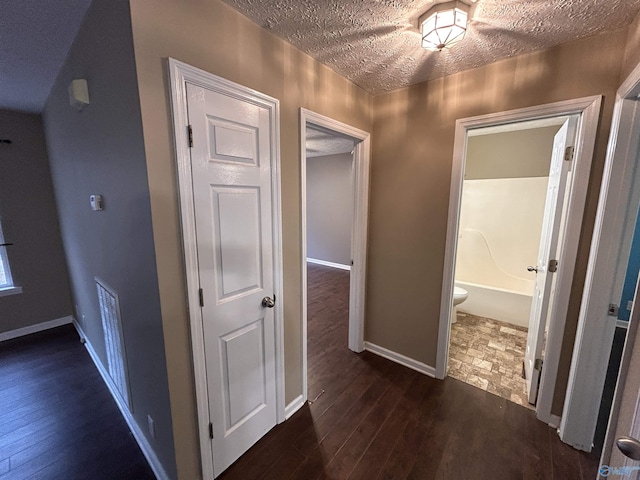 hallway featuring dark hardwood / wood-style flooring and a textured ceiling