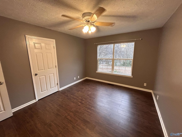 spare room featuring a textured ceiling, ceiling fan, and dark wood-type flooring