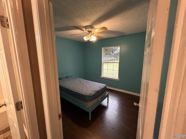 bedroom with a textured ceiling, ceiling fan, and dark wood-type flooring