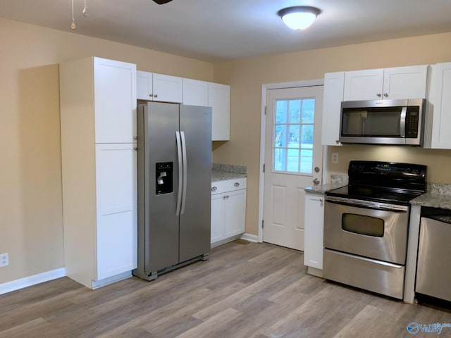 kitchen featuring white cabinetry, light hardwood / wood-style flooring, light stone countertops, and appliances with stainless steel finishes