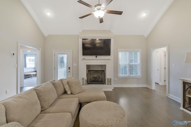 living room with a tiled fireplace, crown molding, dark hardwood / wood-style flooring, and ceiling fan