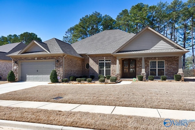 craftsman-style home with a garage, a shingled roof, concrete driveway, and brick siding