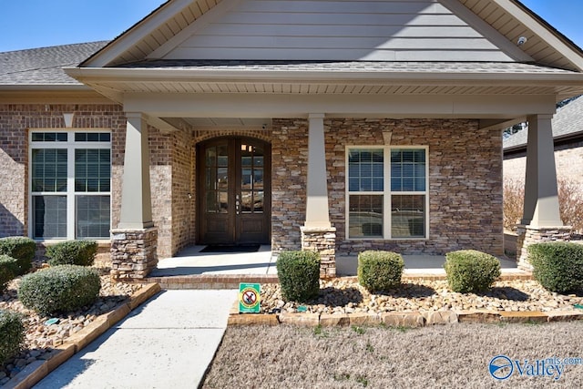 doorway to property featuring covered porch, roof with shingles, brick siding, and french doors