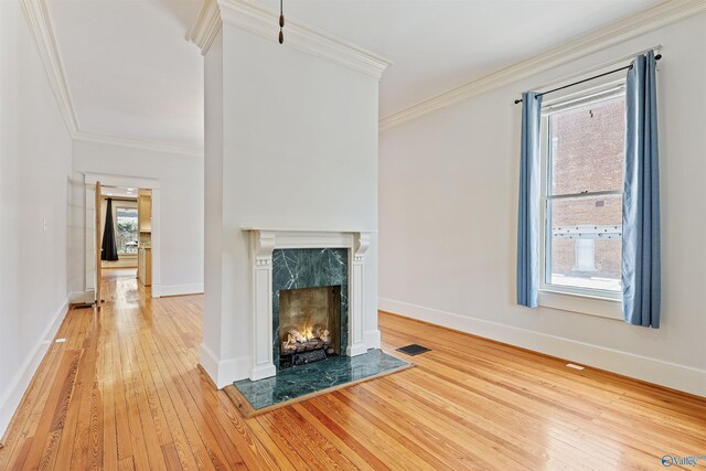 unfurnished living room with light hardwood / wood-style flooring, a fireplace, and crown molding