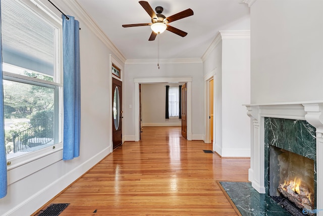 interior space with light hardwood / wood-style floors, ornamental molding, and a healthy amount of sunlight