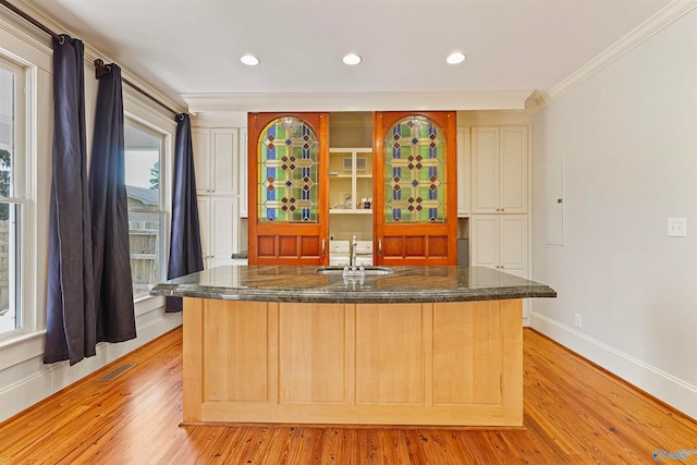 bar featuring light hardwood / wood-style floors, sink, a wealth of natural light, and crown molding