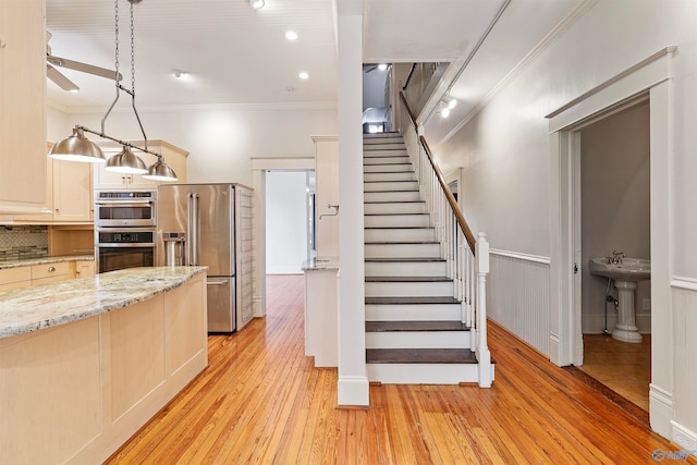 kitchen featuring light hardwood / wood-style floors, ceiling fan, pendant lighting, and stainless steel appliances