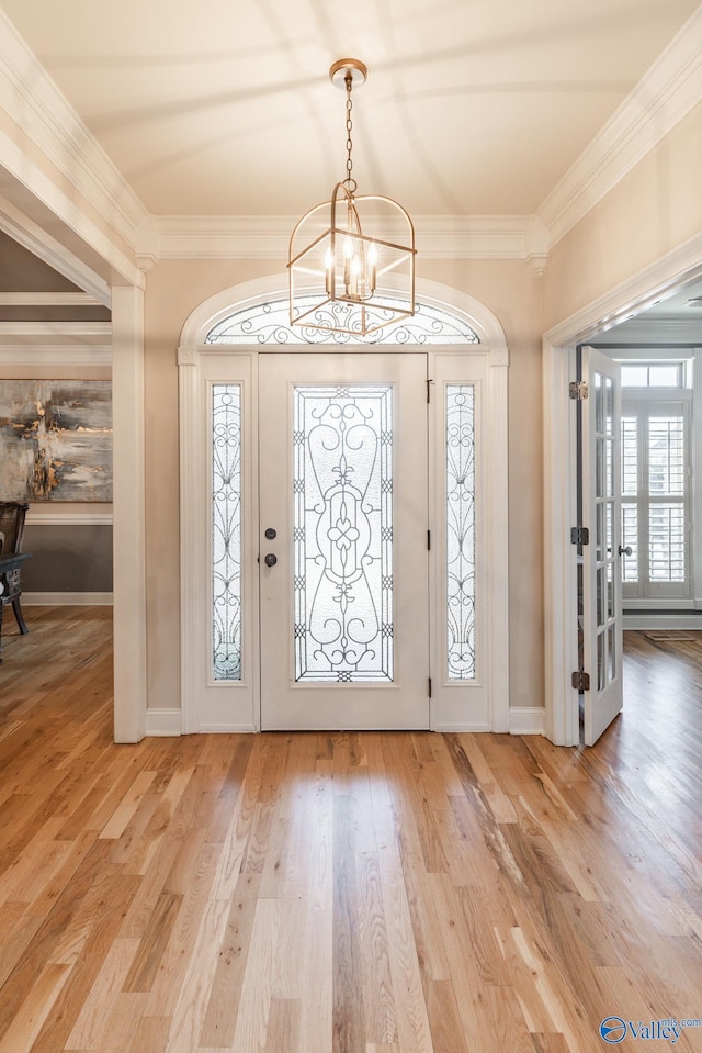 foyer entrance featuring ornamental molding, a chandelier, and wood-type flooring