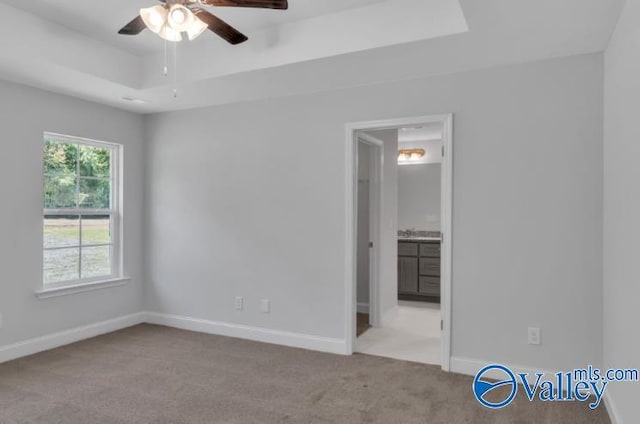 carpeted spare room with a tray ceiling and ceiling fan