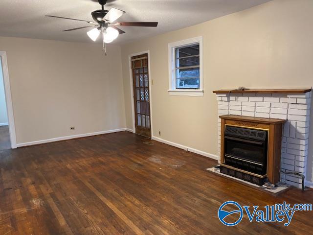 unfurnished living room featuring dark wood-type flooring, ceiling fan, and a fireplace