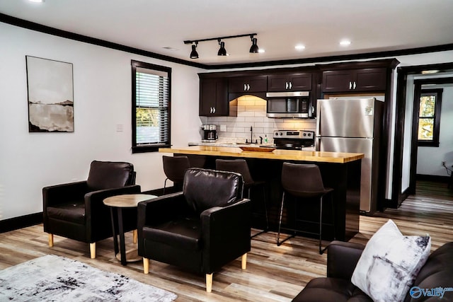 kitchen featuring appliances with stainless steel finishes, light hardwood / wood-style flooring, wood counters, and a breakfast bar area