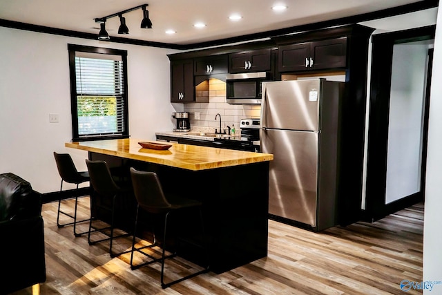 kitchen with crown molding, light hardwood / wood-style flooring, wood counters, stainless steel appliances, and a kitchen island