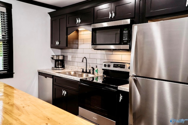 kitchen with appliances with stainless steel finishes, tasteful backsplash, butcher block counters, and sink