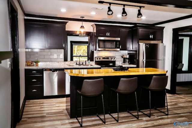 kitchen featuring a center island, butcher block countertops, stainless steel appliances, and light hardwood / wood-style floors