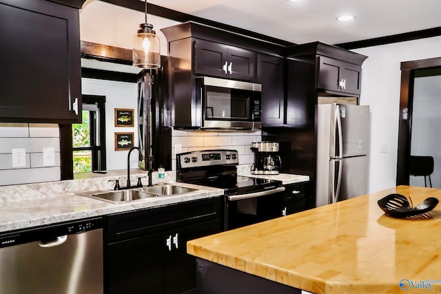 kitchen with pendant lighting, stainless steel appliances, butcher block countertops, sink, and decorative backsplash