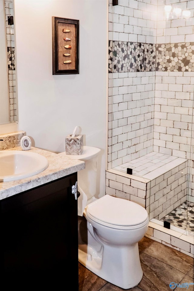 bathroom with vanity, toilet, and a tile shower