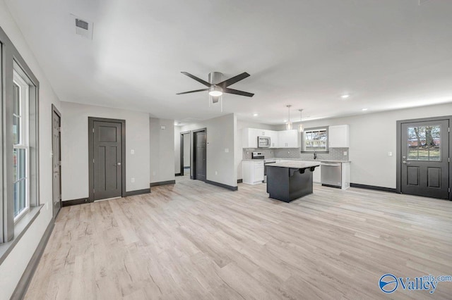 unfurnished living room with a wealth of natural light, ceiling fan, and light wood-type flooring