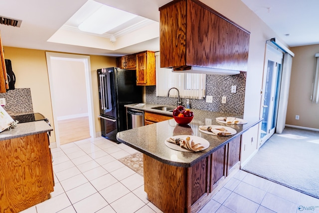 kitchen featuring decorative backsplash, dishwasher, a peninsula, a tray ceiling, and a sink