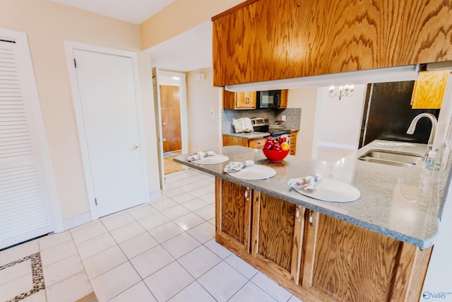 kitchen with electric stove, tasteful backsplash, a sink, black microwave, and a peninsula