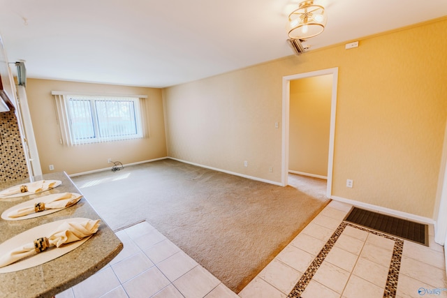 carpeted empty room with baseboards, visible vents, and tile patterned floors