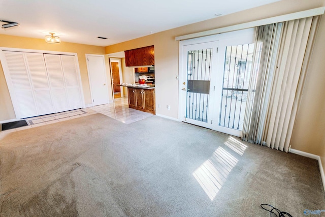 unfurnished living room featuring light carpet, baseboards, and light tile patterned floors