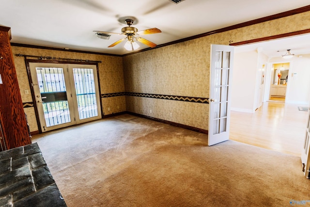 carpeted spare room featuring crown molding, baseboards, visible vents, and wallpapered walls