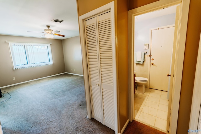 hallway with carpet floors, visible vents, and baseboards