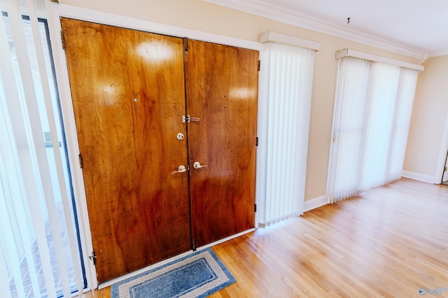 interior space featuring ornamental molding, baseboards, and wood finished floors