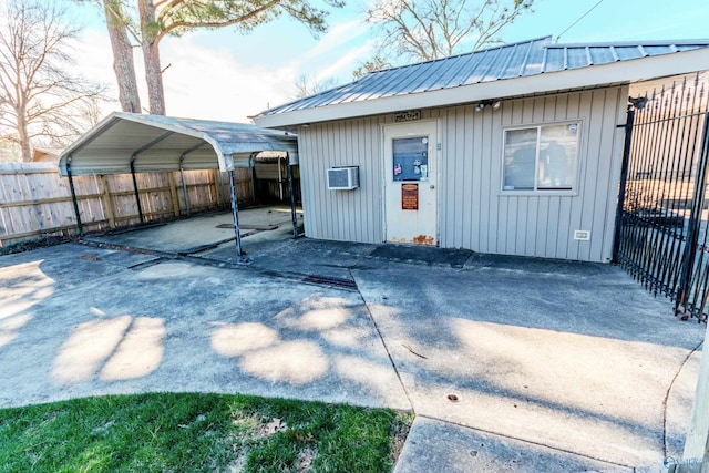 exterior space with a wall mounted AC, fence, a carport, and concrete driveway