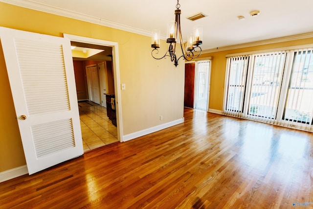 spare room featuring a notable chandelier, baseboards, ornamental molding, and wood finished floors