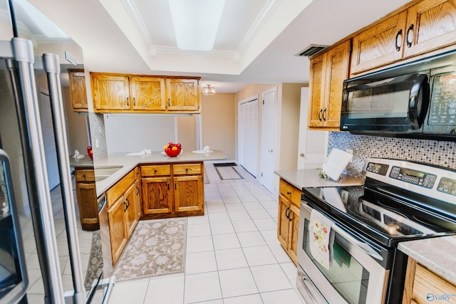 kitchen featuring light countertops, appliances with stainless steel finishes, a tray ceiling, tasteful backsplash, and crown molding